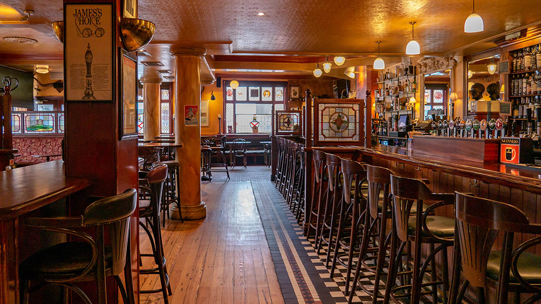 Interior of Fitzgerald's pub showing the wooden bar counter, Guinness taps, and warm lighting